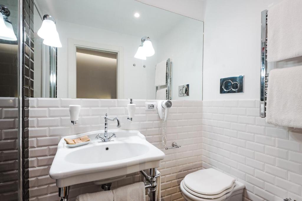 a white bathroom with a sink and a toilet at Nikis Collection Trastevere in Rome