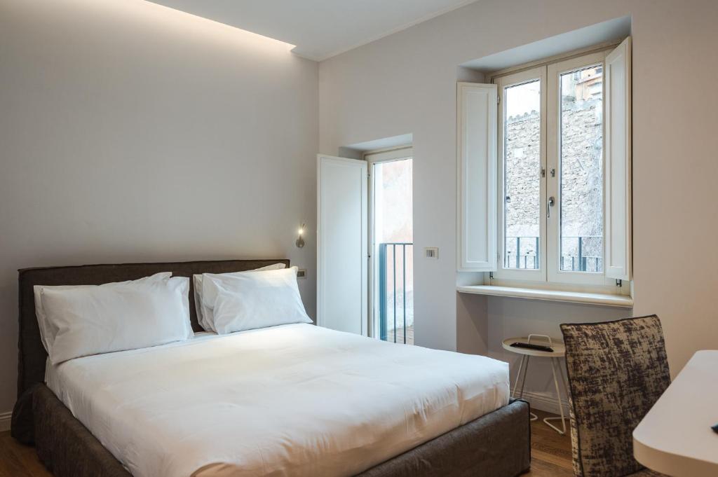 um quarto com uma cama, uma secretária e uma janela em Nikis Collection Trastevere em Roma