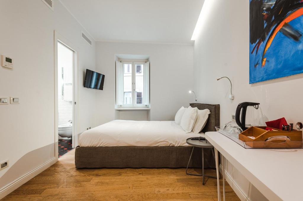 a white bedroom with a bed and a desk at Nikis Collection Trastevere in Rome