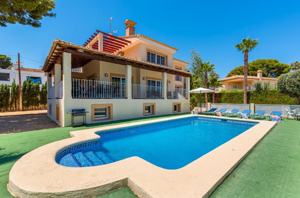 a villa with a swimming pool in front of a house at Villa Dorada - PlusHolidays in Calpe