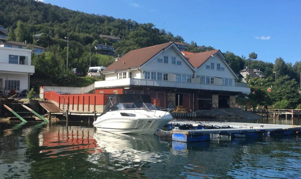 ein Boot, das an einem Dock vor einem Haus angedockt ist in der Unterkunft Fjord Apartments in Dimmelsvik