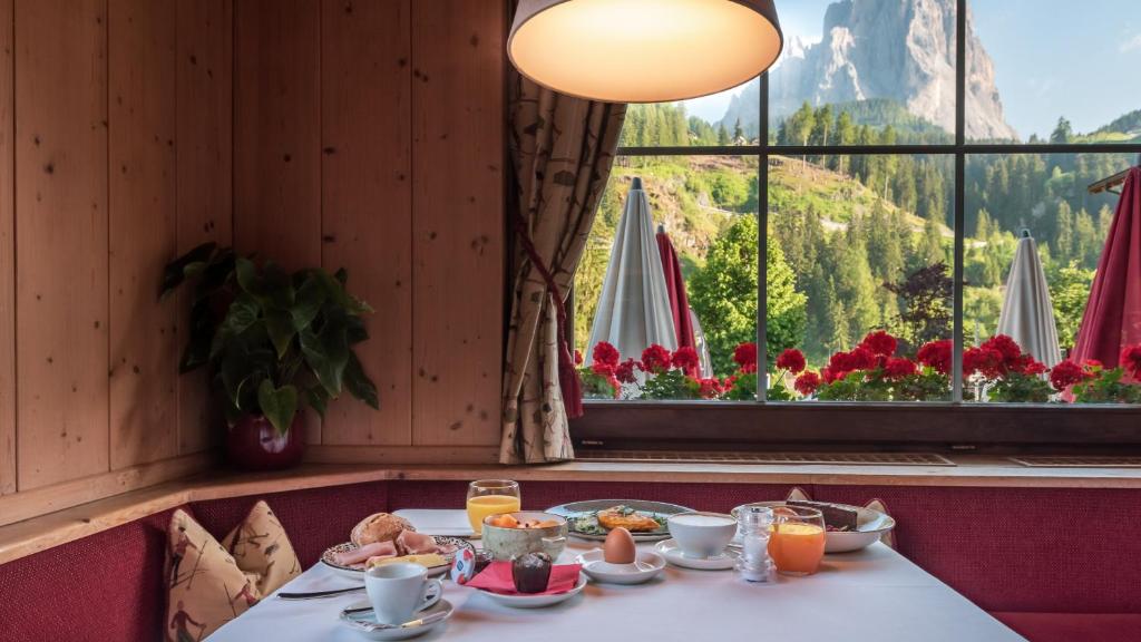 una mesa con comida delante de una ventana en B&B La Tambra - central with Restaurant en Santa Cristina in Val Gardena