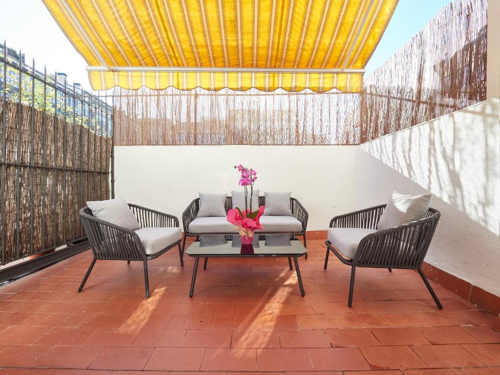 eine Terrasse mit 2 Stühlen und einem Tisch mit Blumen darauf in der Unterkunft Barcelonaforrent The Living Apartment in Barcelona