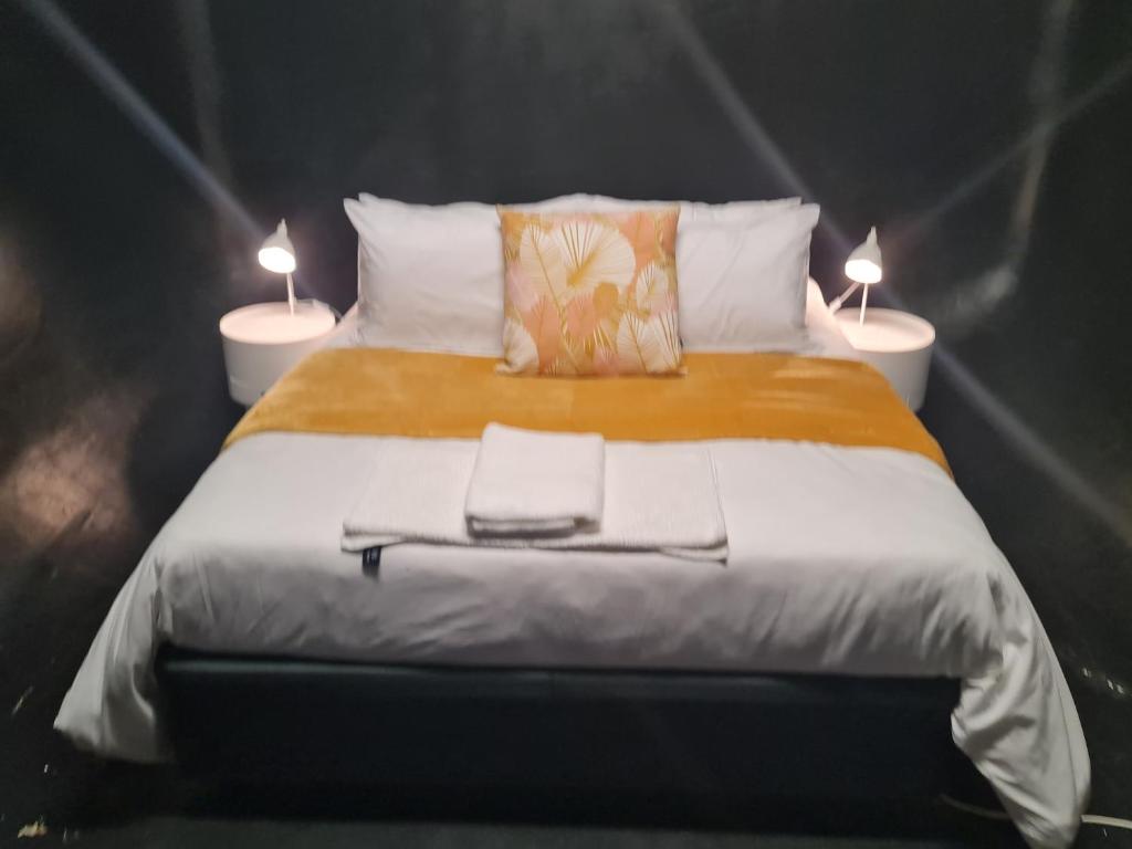 a large bed with two lamps on top of it at The Hide-Pit Stop in East London