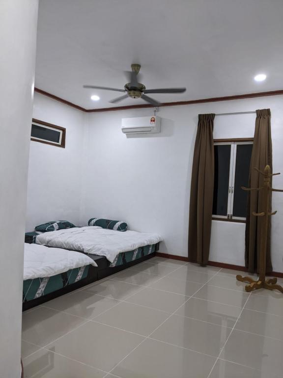 1 dormitorio con 2 camas y ventilador de techo en Denai Senja, en Kuala Selangor