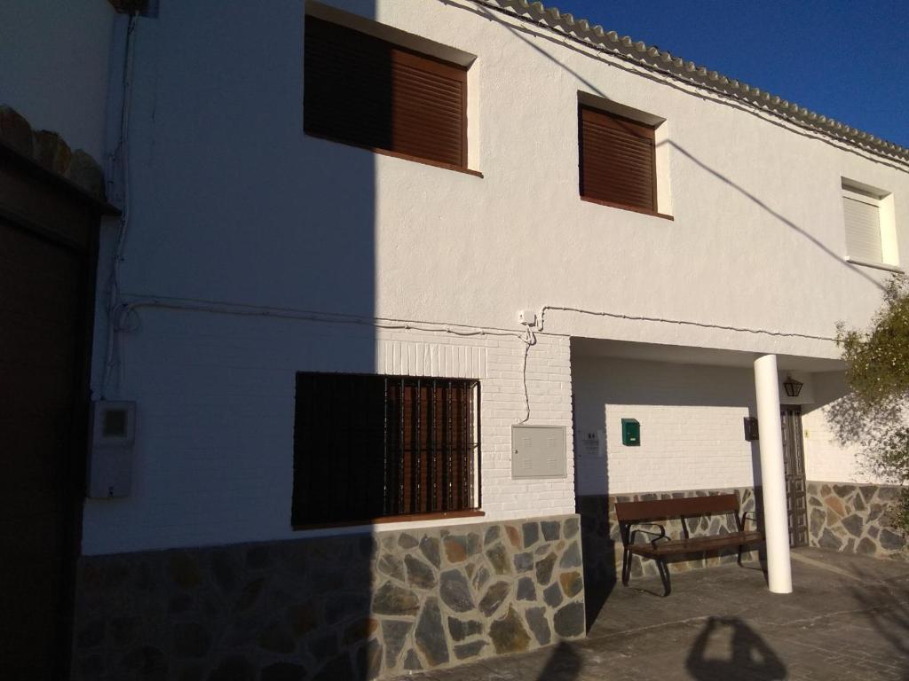 Casa Rural El Albergue في Beires: مبنى ازرق وابيض وامامه مقاعد