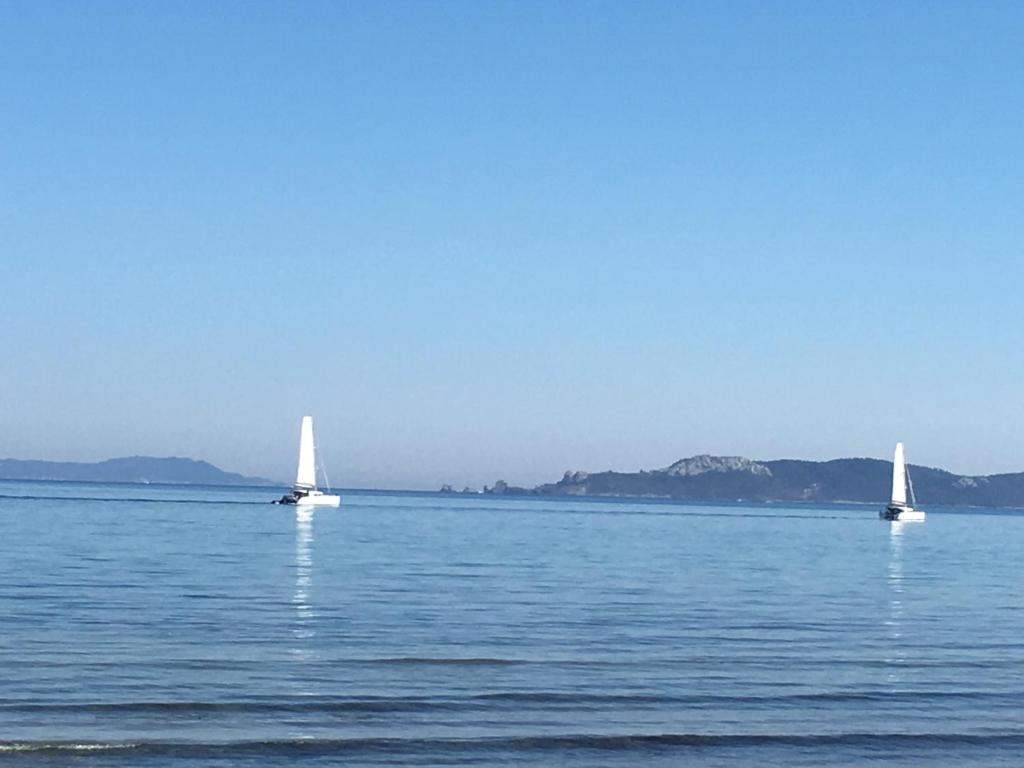 three sailboats on the water with mountains in the background at Les Sables d'Or in Hyères