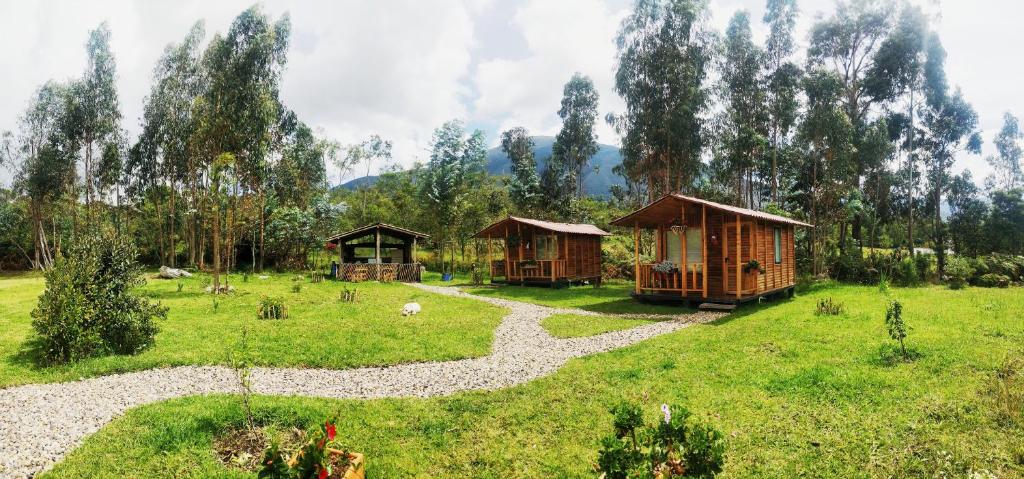a group of huts in a field with a path at Casa de Leña - Cabaña Rural in Villa de Leyva