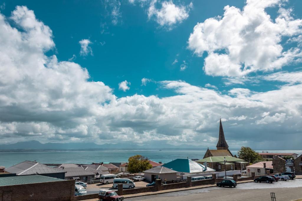 a town with a church and a blue sky with clouds at Sandstone Manor in Mossel Bay