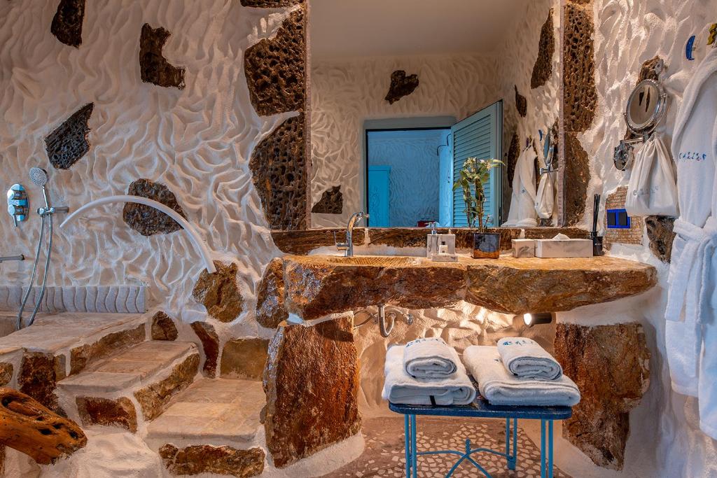 uma grande casa de banho em pedra com um lavatório e um espelho em Calilo em Manganari