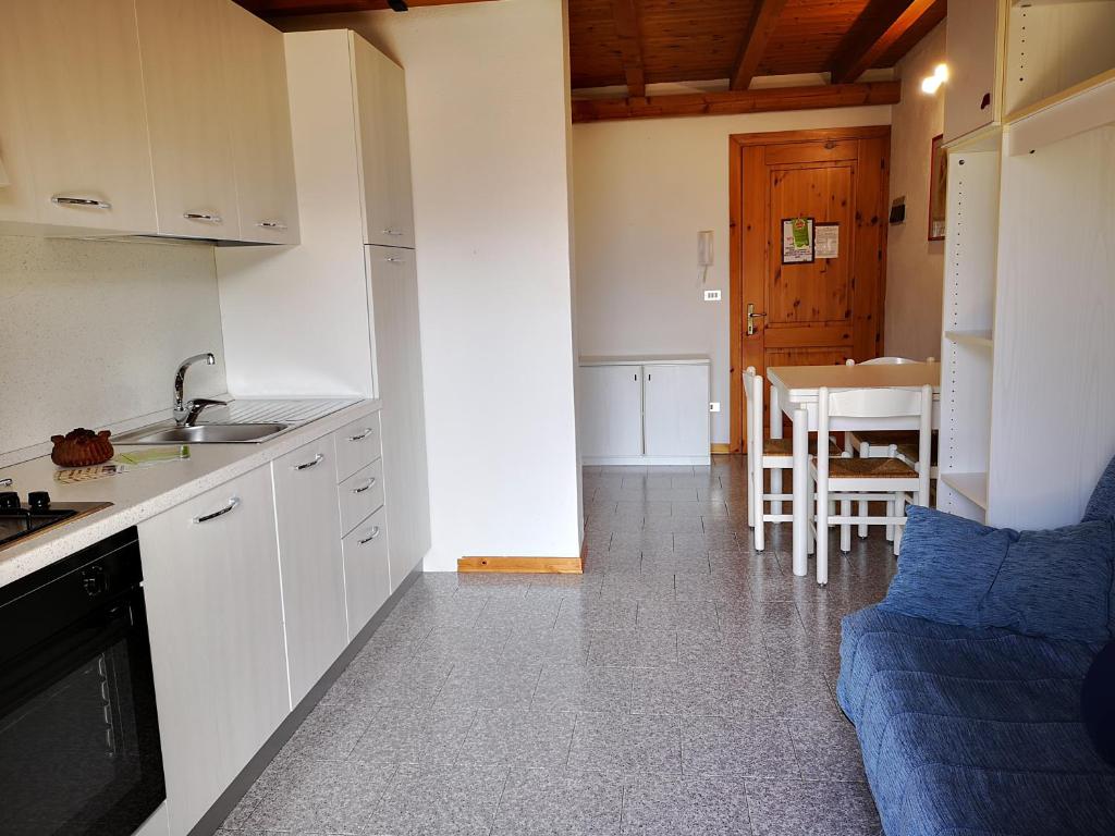 una cocina con armarios blancos y un sofá azul en una habitación en Giò Appartamenti Vacanze, en Aymavilles