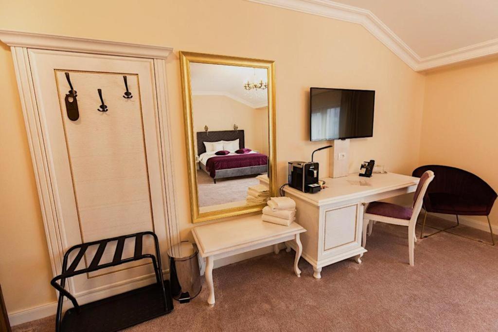 a room with a desk and a bed with a mirror at 4Cardinal's Hotel Boutique in Braşov