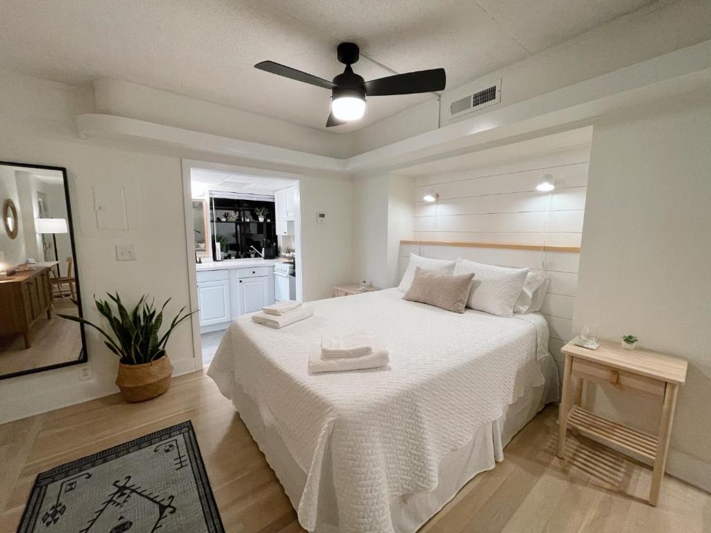 Un dormitorio con una cama blanca con ventilador de techo. en Just Shy of the Bridge - Waterway Condo 110, en Wilmington