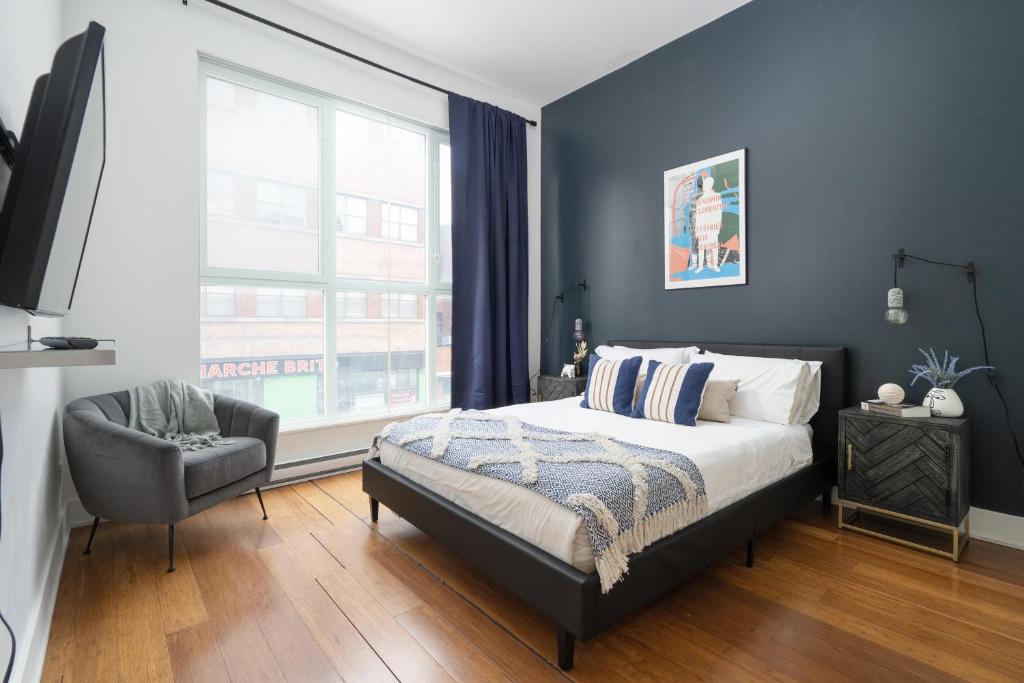 a bedroom with a bed and a chair and a window at Hotel-Apart Prince Arthur in Montréal