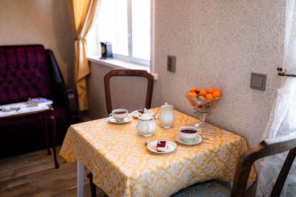 a table with cups and saucers and a bowl of oranges at Campenhausen lodging in the heart of Kuressaare in Kuressaare