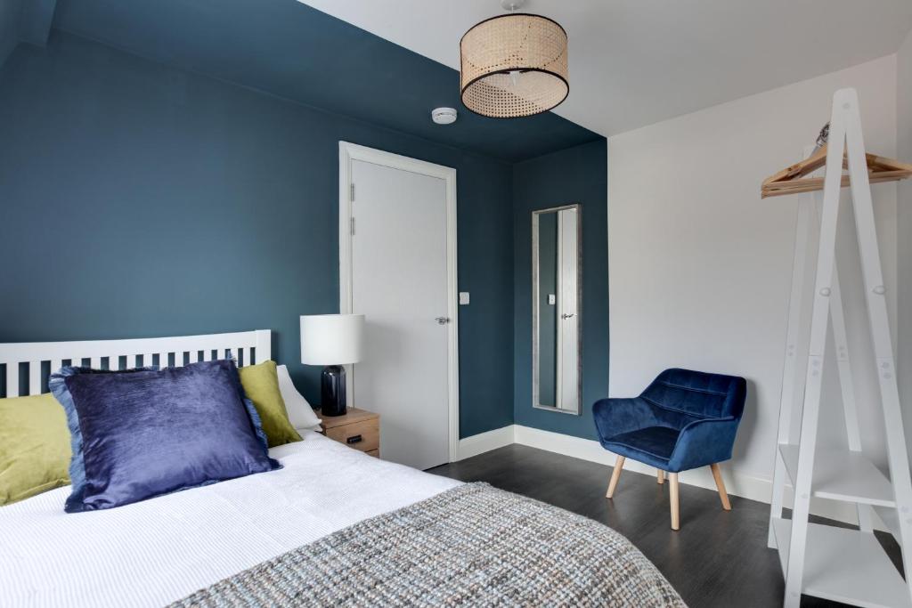 1 dormitorio con paredes azules, 1 cama y 1 silla azul en Beautiful Chelmsford Apartment, en Chelmsford