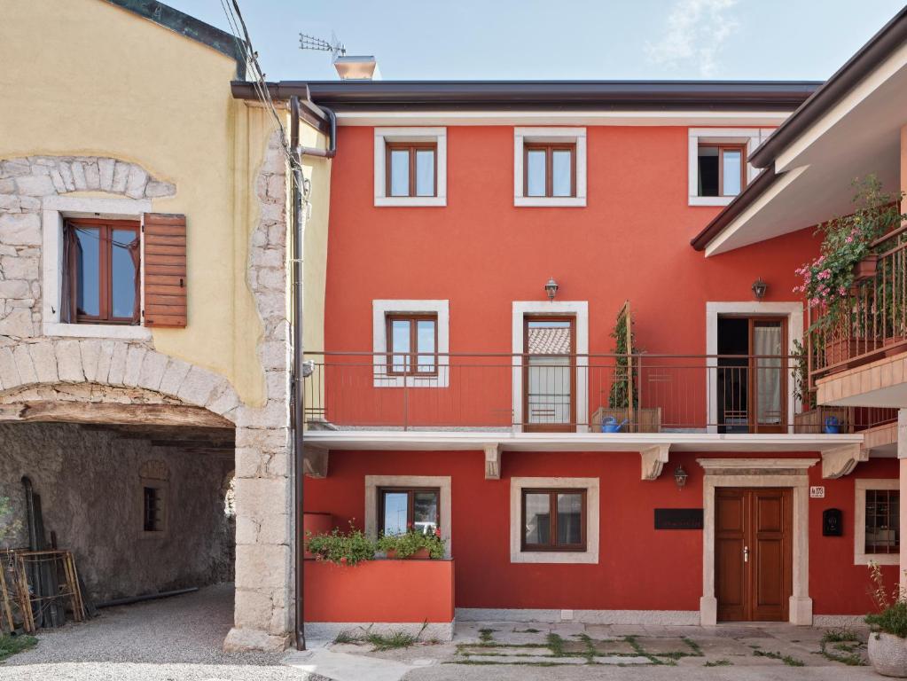 a red house with a balcony in a courtyard at Crocevia - Locanda carsica contemporanea in Trieste
