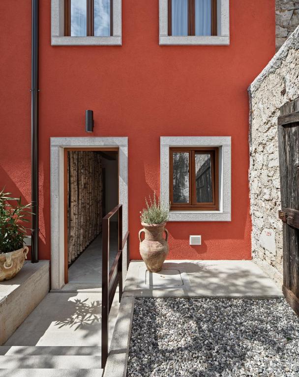 a red house with a vase sitting in front of it at Crocevia - Locanda carsica contemporanea in Trieste
