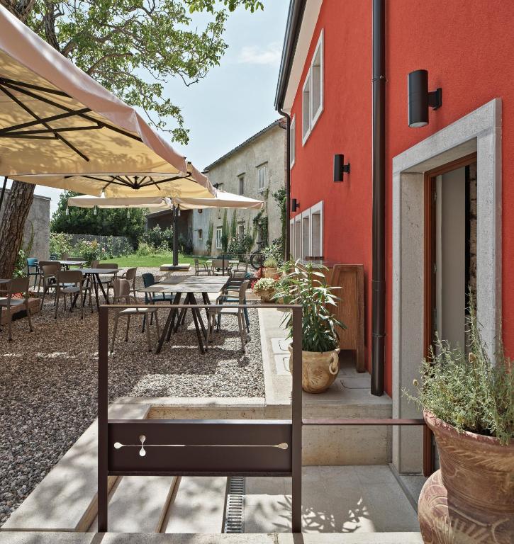 a patio with tables and umbrellas next to a building at Crocevia - Locanda carsica contemporanea in Trieste