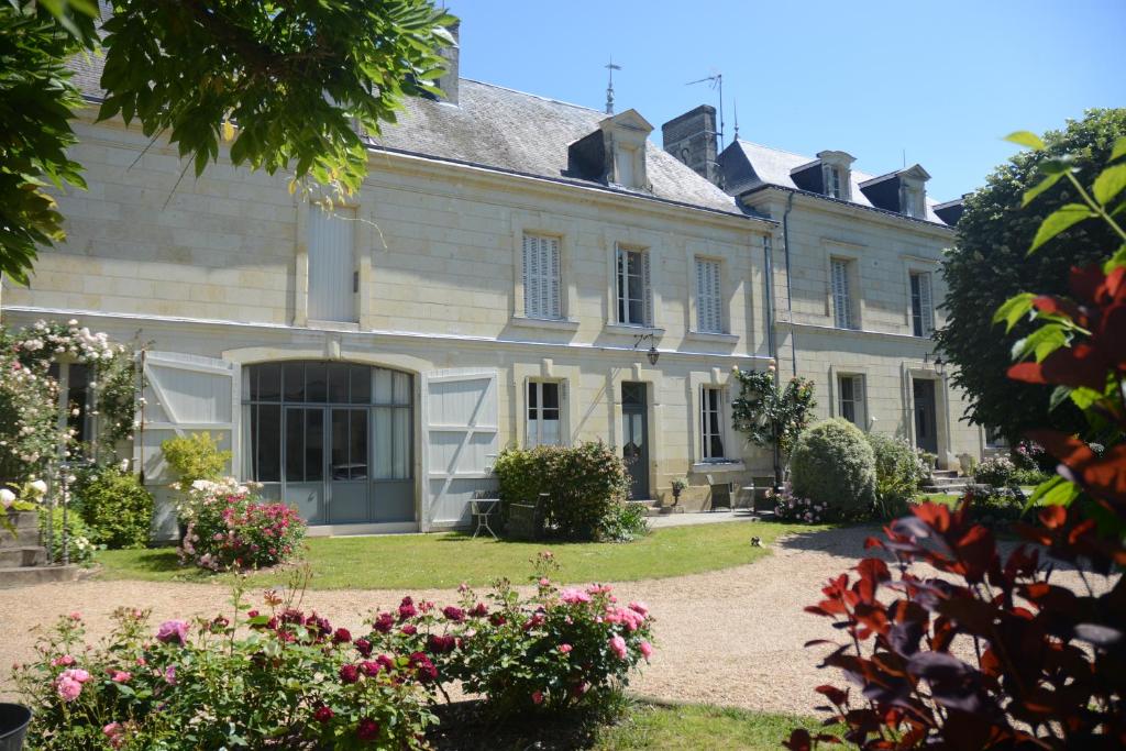 a large white house with flowers in the yard at La Pénesais in Beaumont-en-Véron