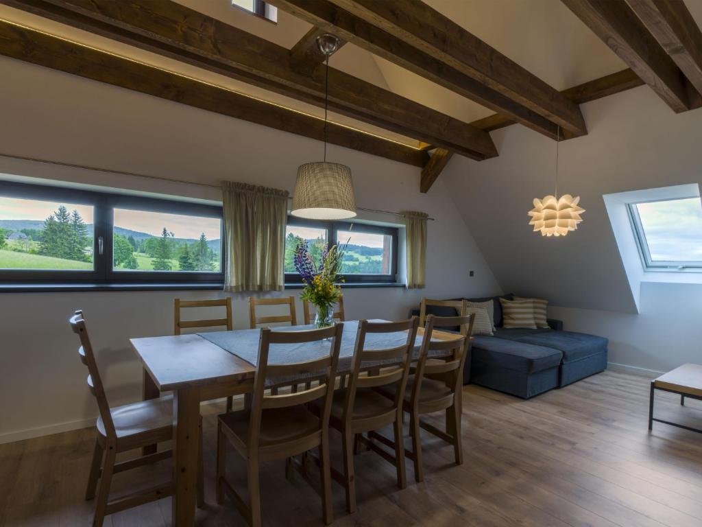 a dining room with a table and chairs and a couch at Apartmán pod Pustým vrchem in Říčky