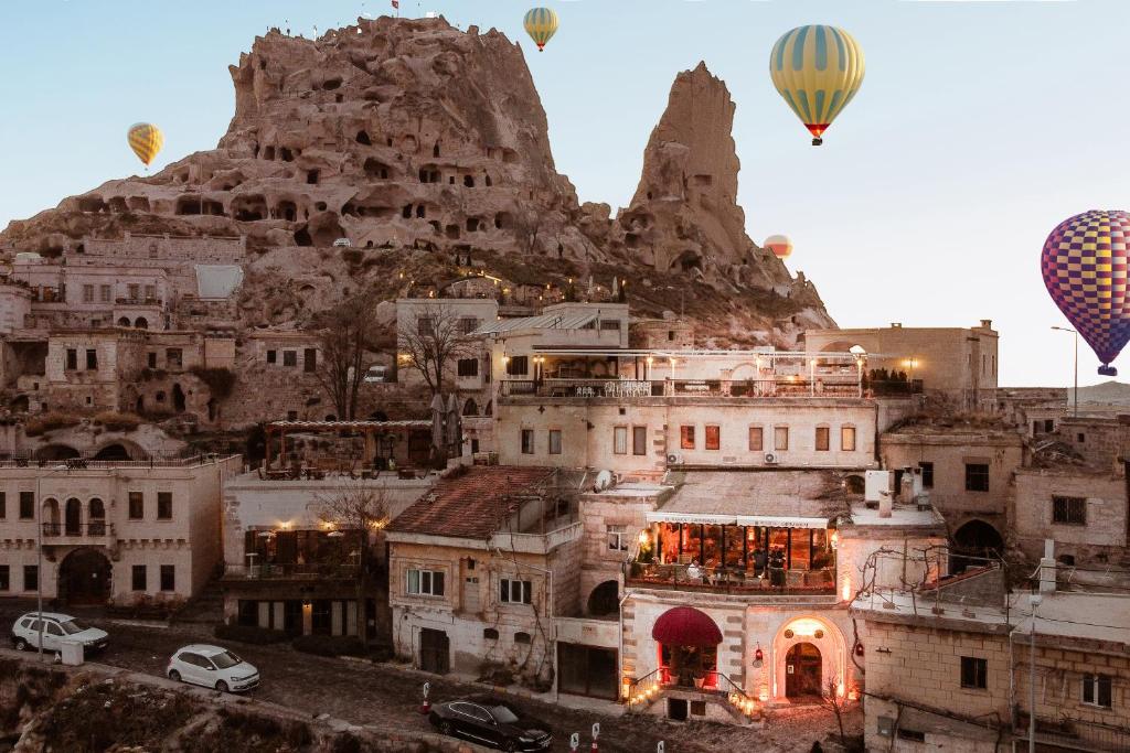 a group of hot air balloons flying over a city at Hu of Cappadocia - Special Class in Uchisar