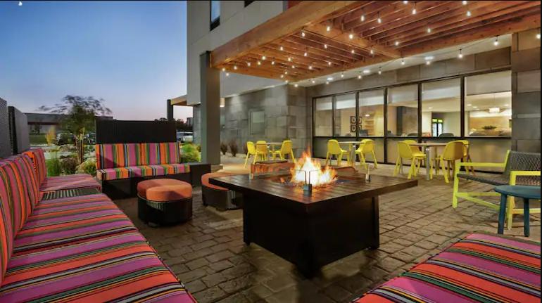 un patio con una hoguera, mesas y sillas en Home2 Suites By Hilton Columbus/West, OH, en Columbus