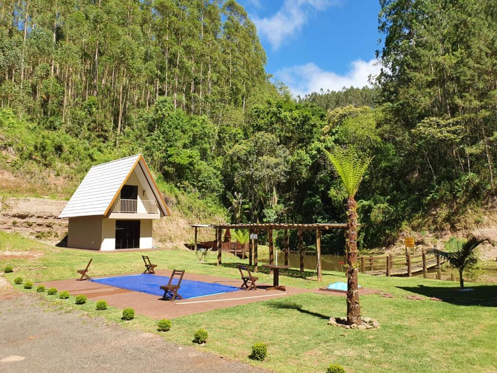 a small cabin with a playground and a tree at Recanto da Serra Chalé 02 in Mauá da Serra