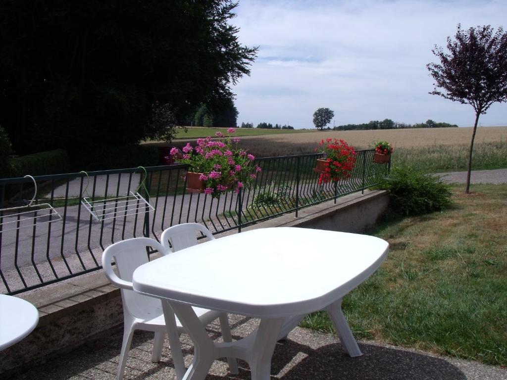 a white table and chairs and a fence with flowers at Gîte Les Hirondelles in Plombières-les-Bains