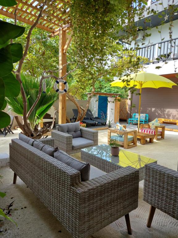 eine Terrasse mit Sofas, Tischen und einem Sonnenschirm in der Unterkunft Palms Retreat in Fulhadhoo