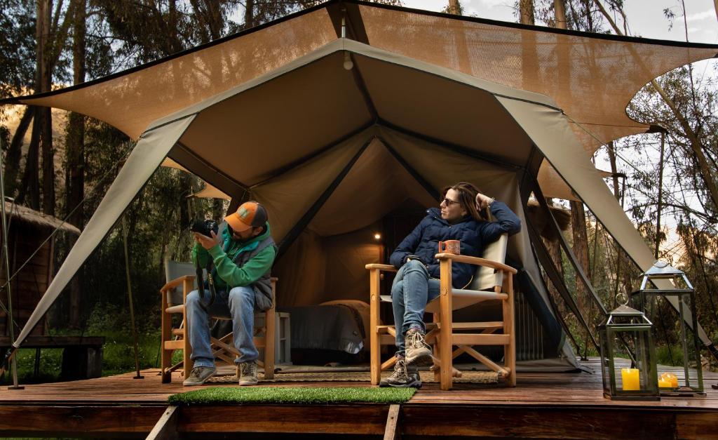 un homme et une femme assis dans une tente dans l'établissement Glamping Chaska Ocupi, à Urubamba