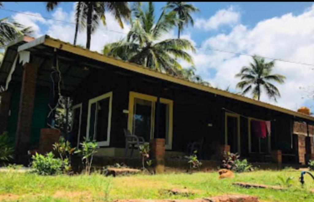 una casa negra con palmeras delante en RiverStone RiverFront FarmHouse, en Gokarna