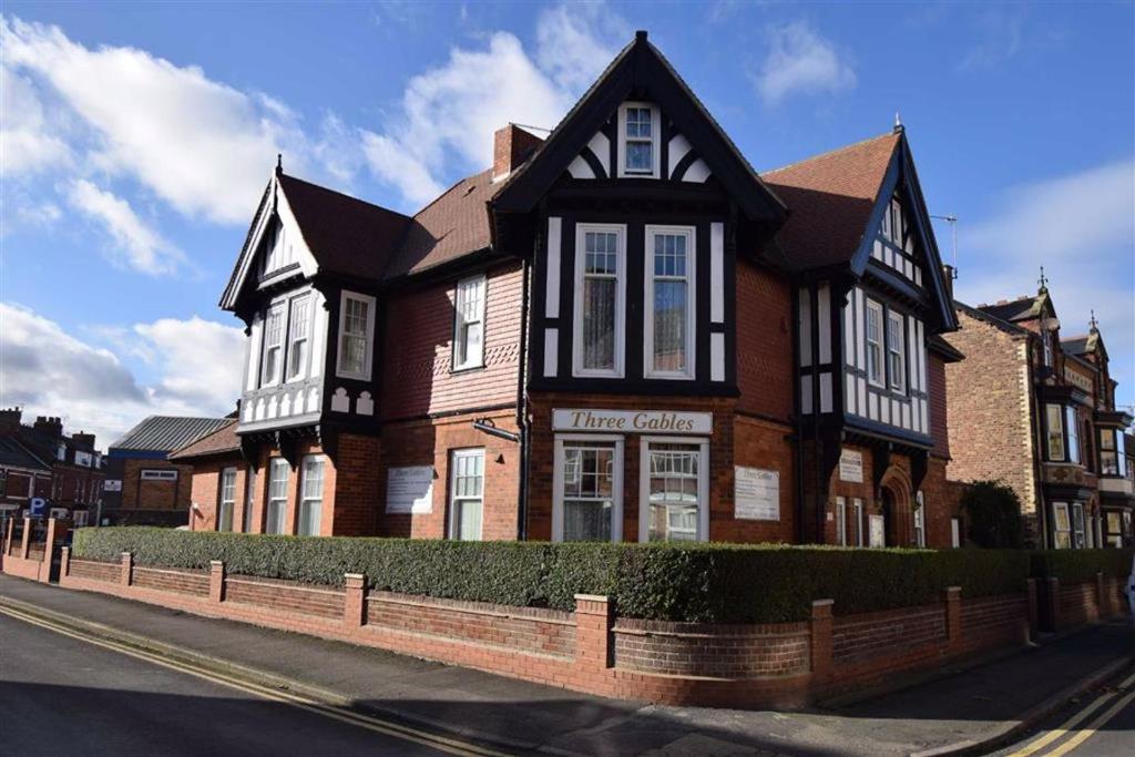 une maison brune et noire sur le côté d'une rue dans l'établissement Three Gables, à Bridlington