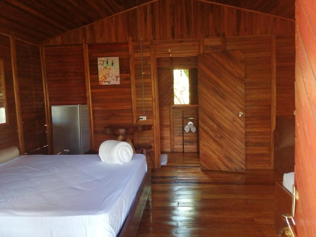 1 dormitorio con 1 cama, paredes de madera y suelo de madera en Cabañas Los Laguitos Rio Celeste en El Achiote