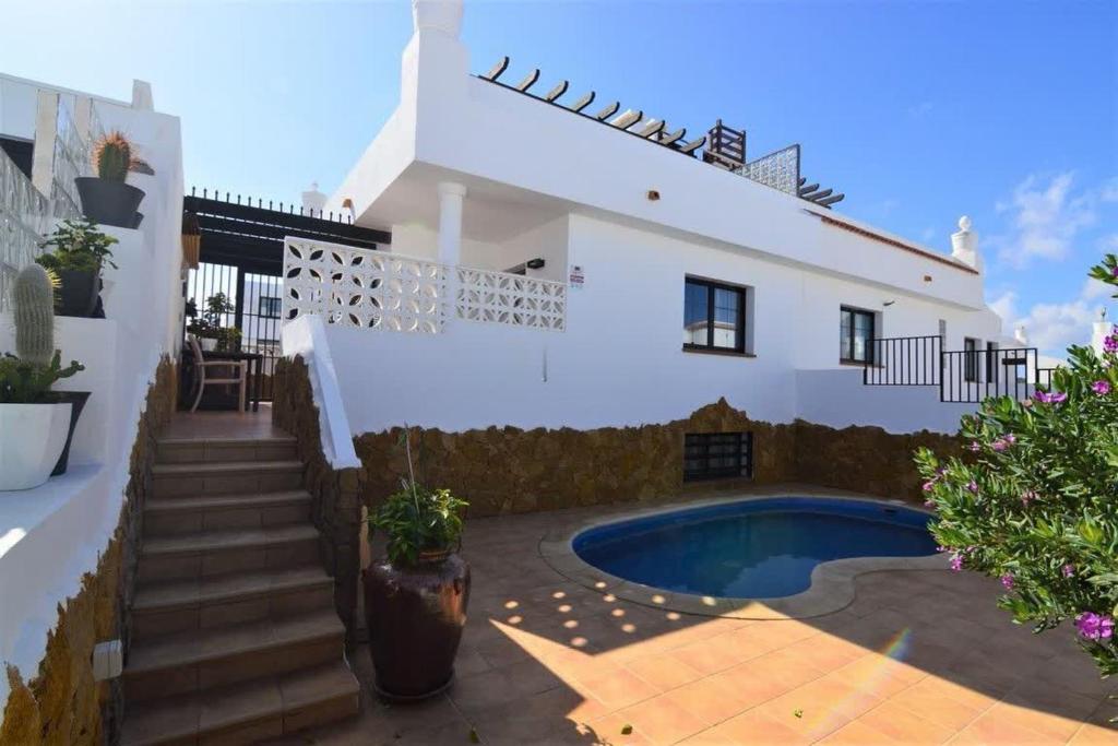 a white house with a swimming pool and stairs at Coco Surfhouse - Coworking Coliving in Corralejo