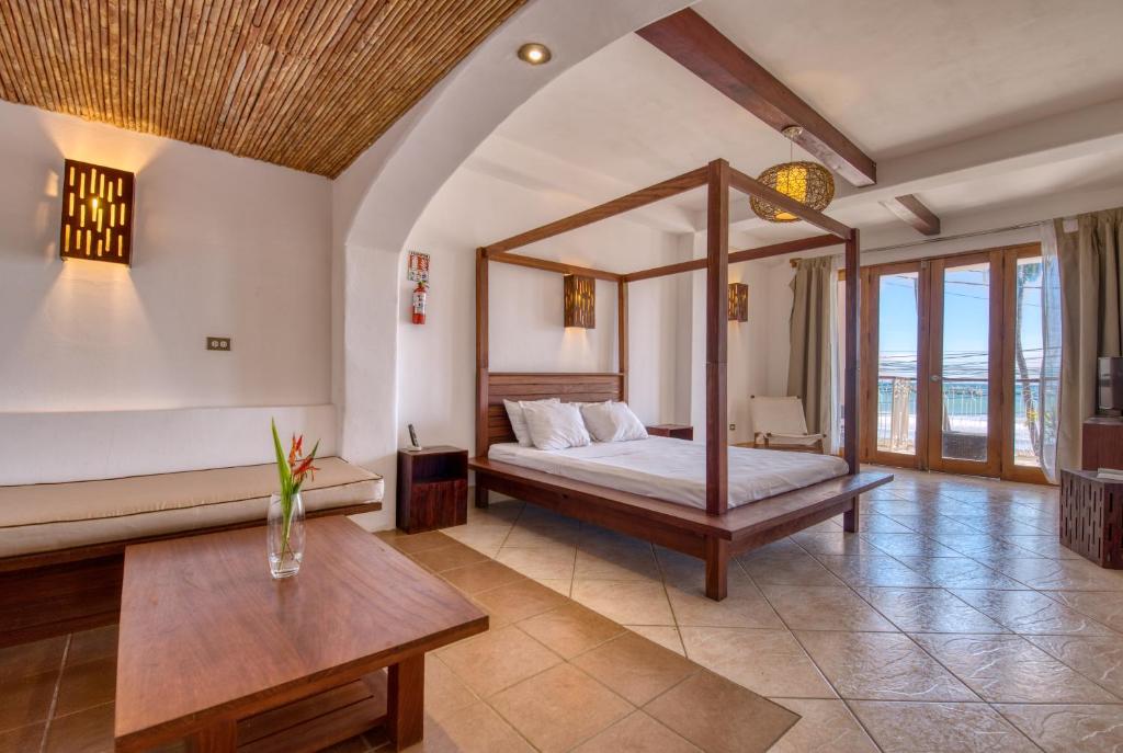 a bedroom with a canopy bed and a table at Hotel Alcazar in San Juan del Sur
