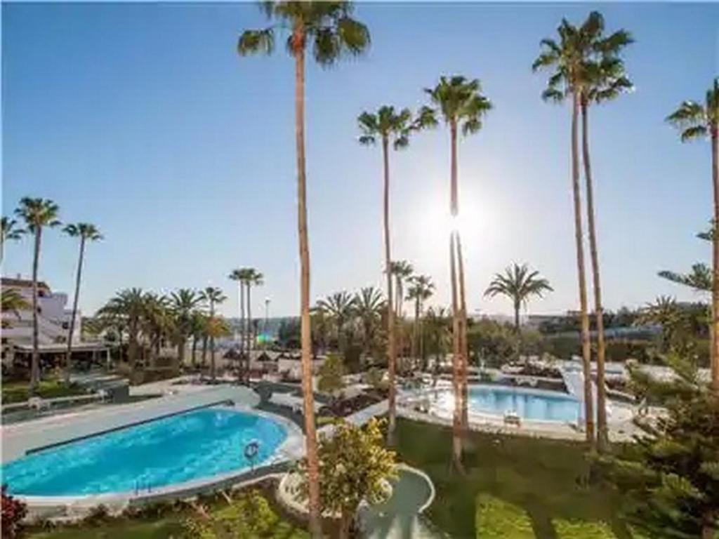 a resort with two pools and palm trees at PARADISE VIEW APARTMENT MASPALOMAS in Maspalomas