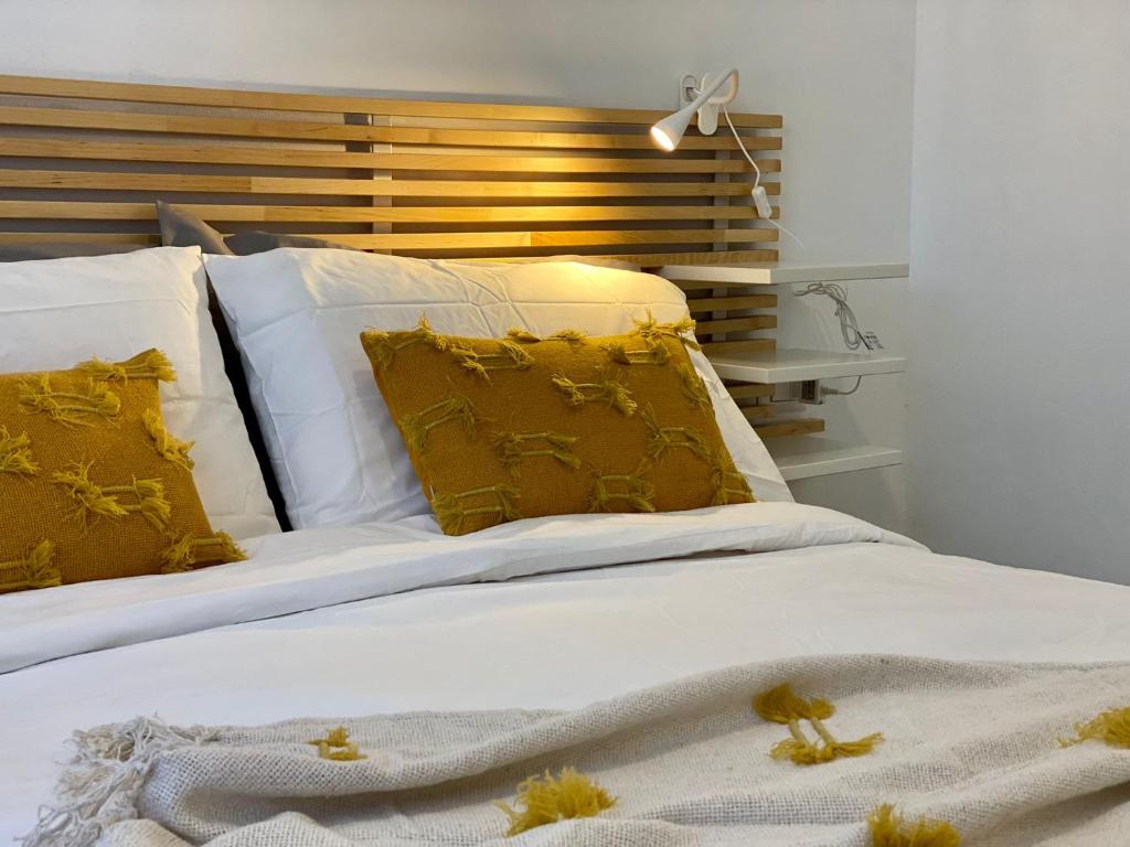 een bed met witte lakens en gele kussens bij Vivapartments MilanoSanSiro in Milaan