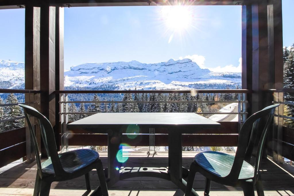 a table and chairs on a balcony with a view at South-facing newly renovated 2-bed apartment Les Terrasses d'Eos in Flaine