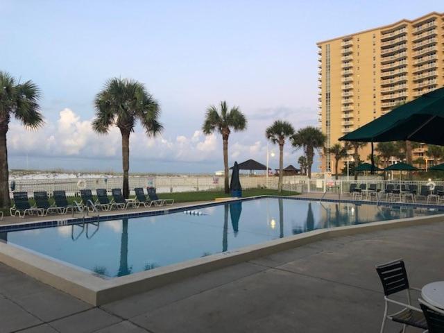 a swimming pool with chairs and palm trees and a building at Destin Holiday Beach Resort in Destin