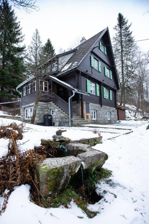 duży czarny dom z śniegiem na ziemi w obiekcie Rakouská vila w mieście Bělá pod Pradědem
