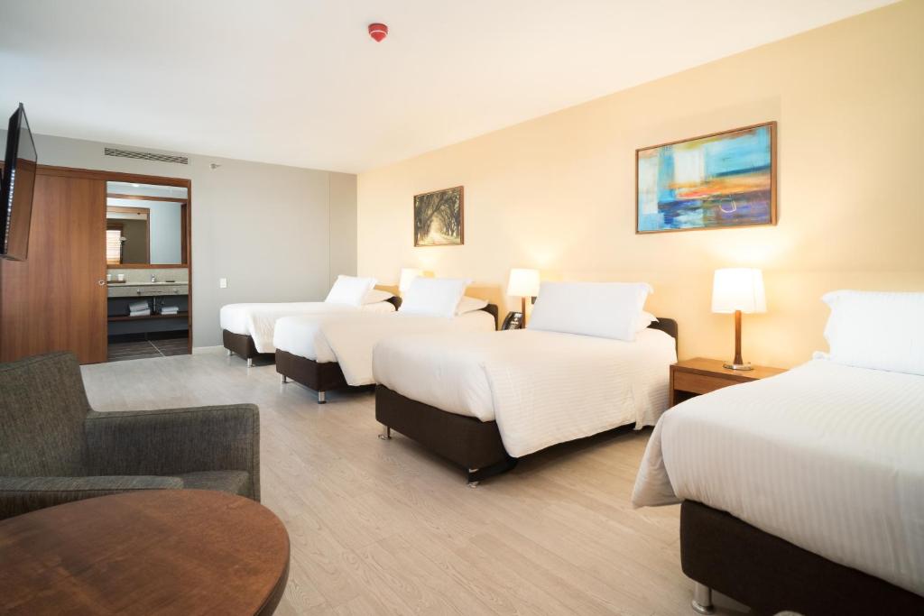a hotel room with four beds and a table at Hotel Habitel Select in Bogotá