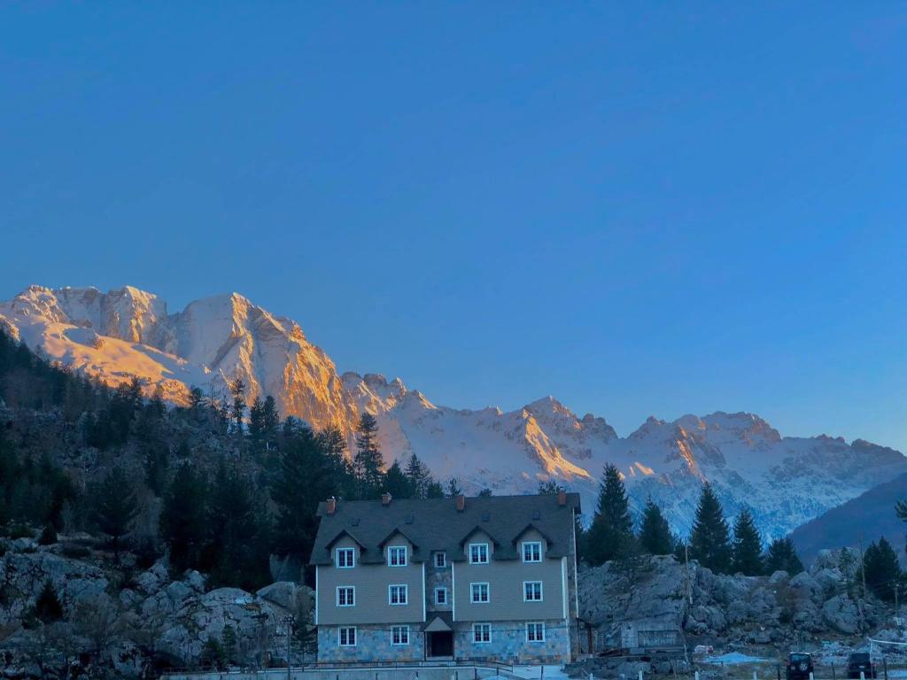 ein Haus auf einem Hügel mit Bergen im Hintergrund in der Unterkunft BUJTINA Valbonë in Valbonë