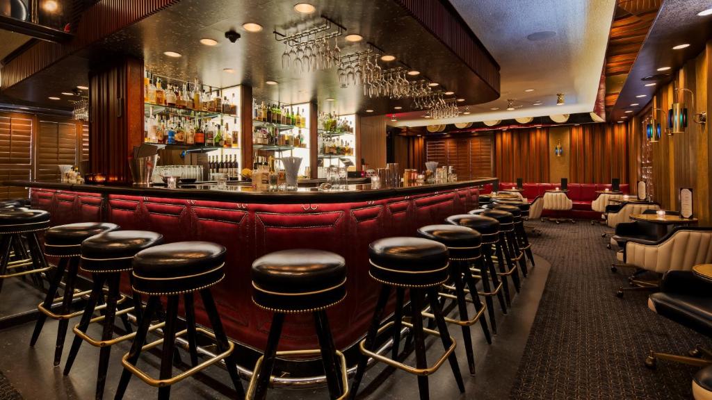 ロサンゼルスにあるThe Adler a Hollywood Hotelの革張りのスツールが備わるバー