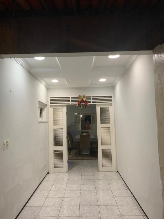 um corredor com paredes brancas e um quarto com uma porta em Sua casa fora de casa em Fortaleza