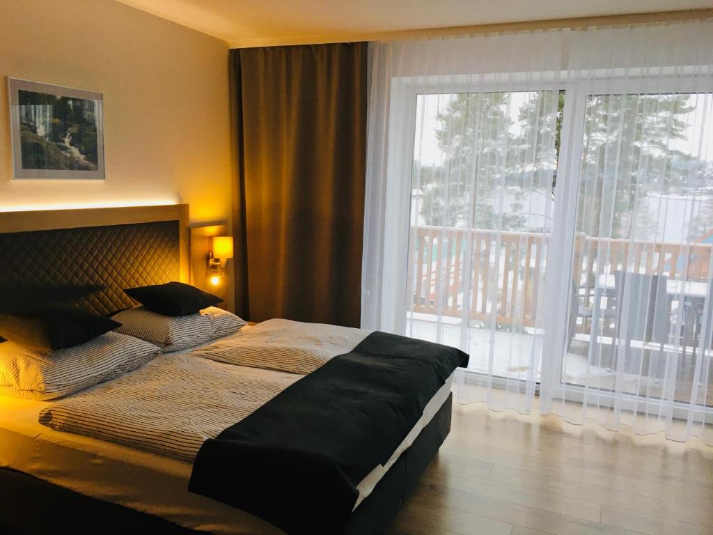 リプノ・ナト・ヴルタヴォウにあるLipno Beach Apartmentの大きなベッドと大きな窓のある寝室