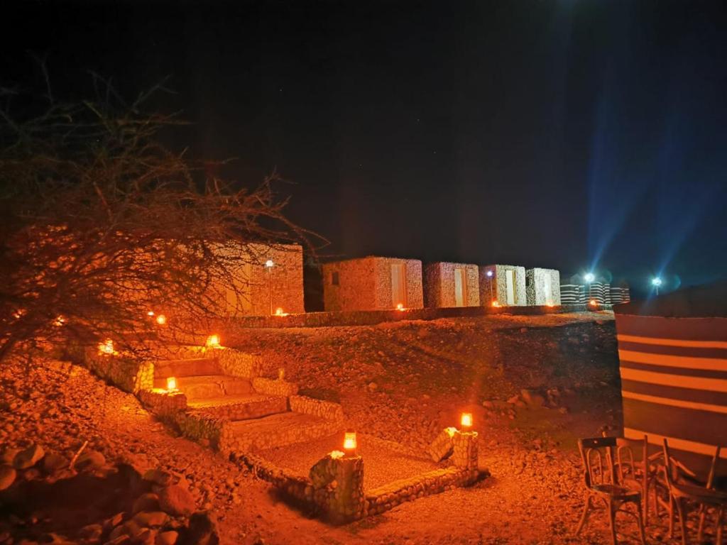 um conjunto de escadas com velas na areia à noite em Wadi Ghwere Camp مخيم وادي الغوير em Al Khuraybah