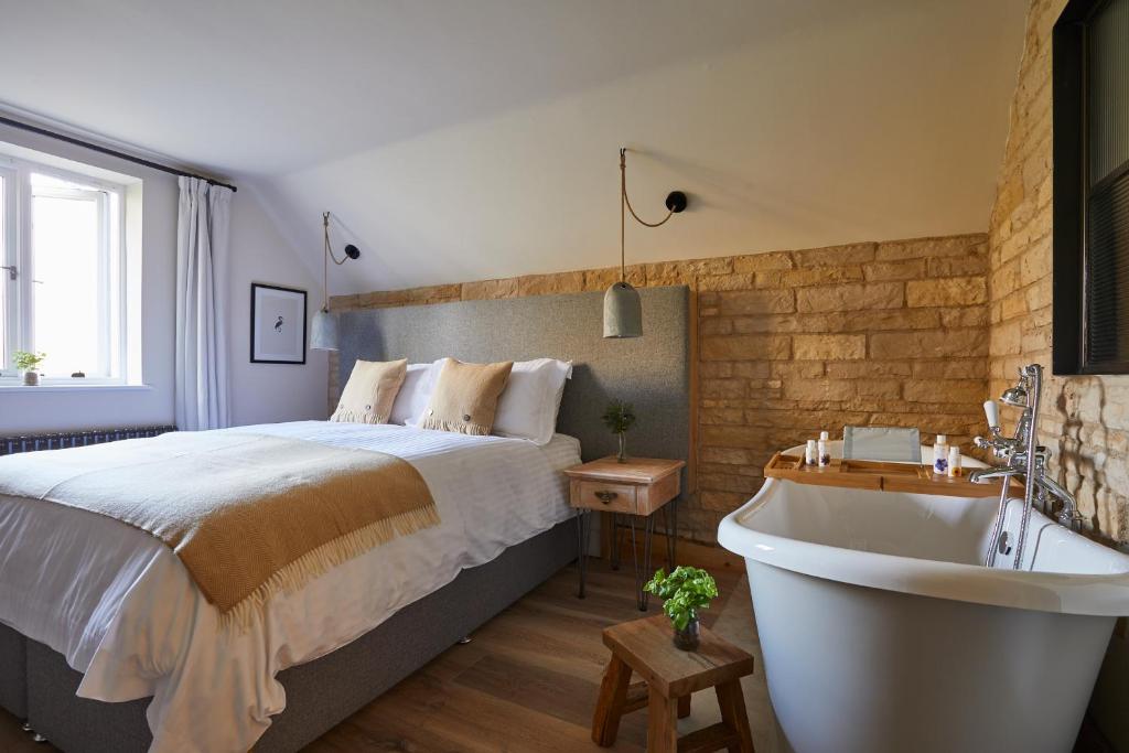 a bedroom with a large bed and a bath tub at Wild Thyme & Honey in Cirencester