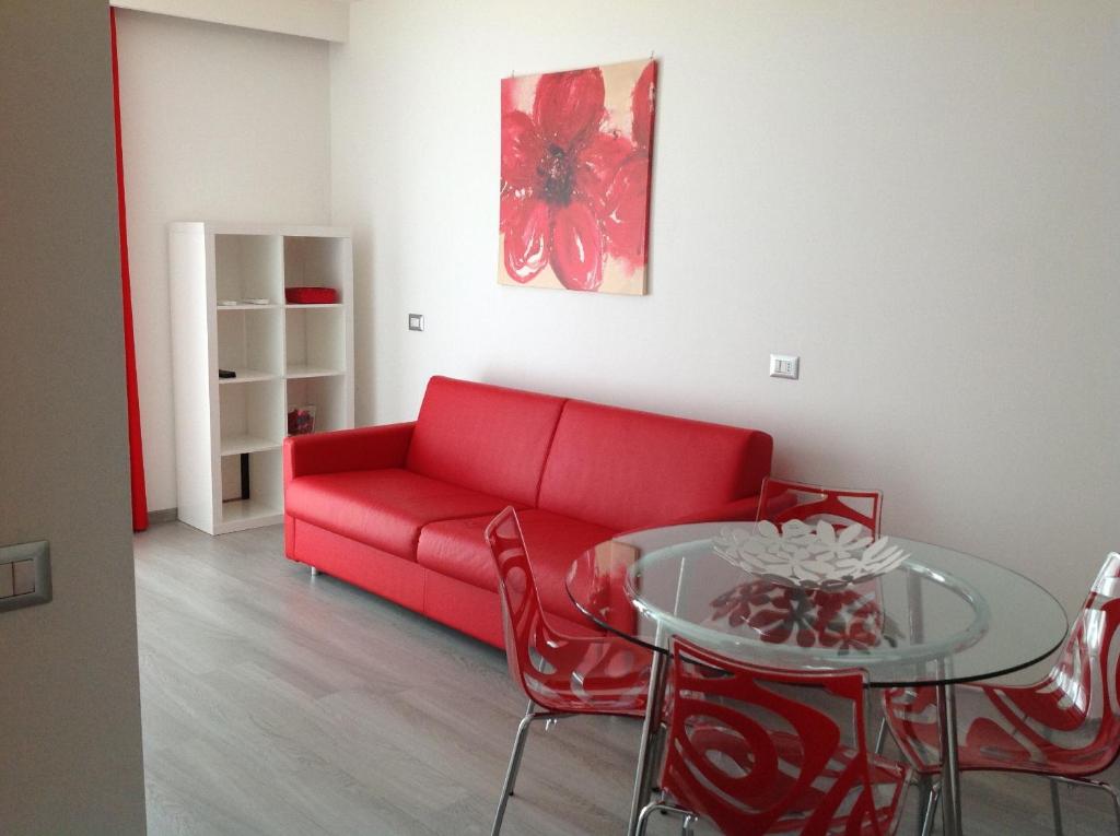 un soggiorno con divano rosso e tavolo di Appartamenti Villa Padania a Malcesine