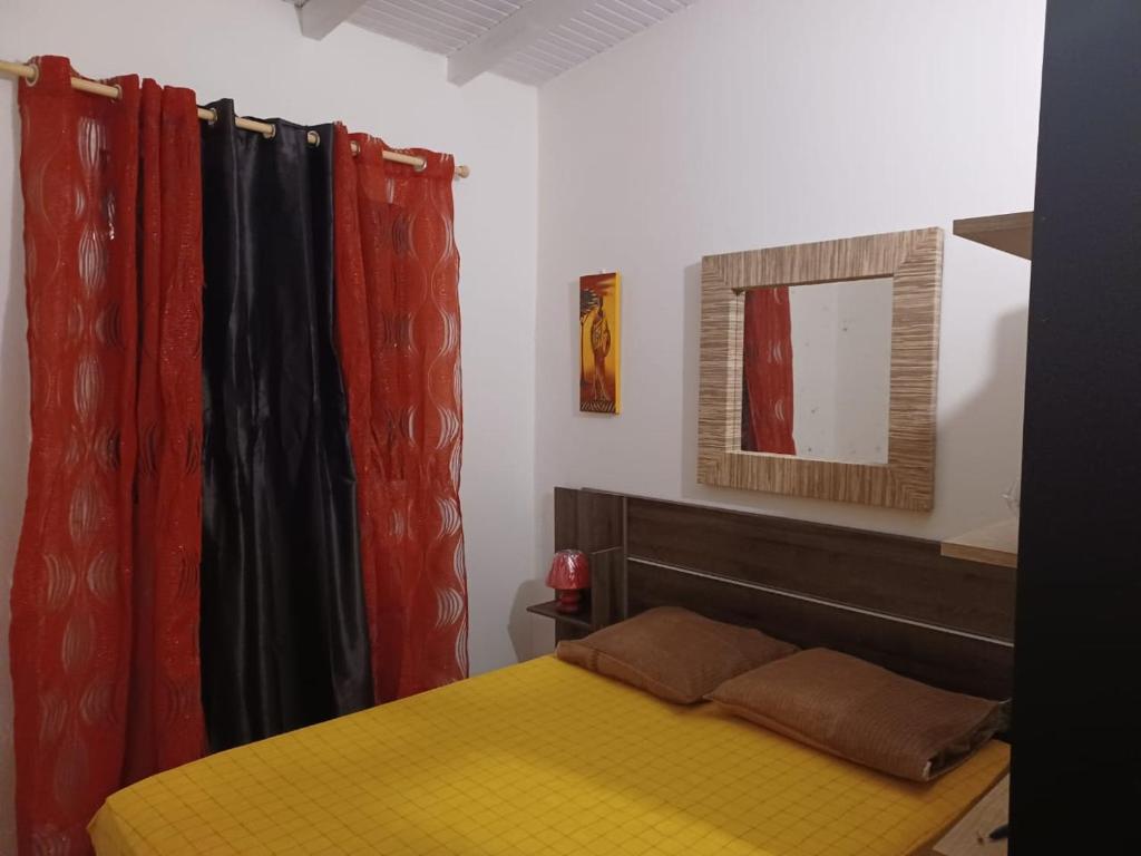 a bedroom with a yellow bed and red curtains at Charmant bungalow du Moule in Le Moule